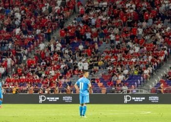 A candid image of Sunil Chhetri walking off the pitch, looking reflective, with fans blurred in the background.
