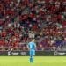A candid image of Sunil Chhetri walking off the pitch, looking reflective, with fans blurred in the background.
